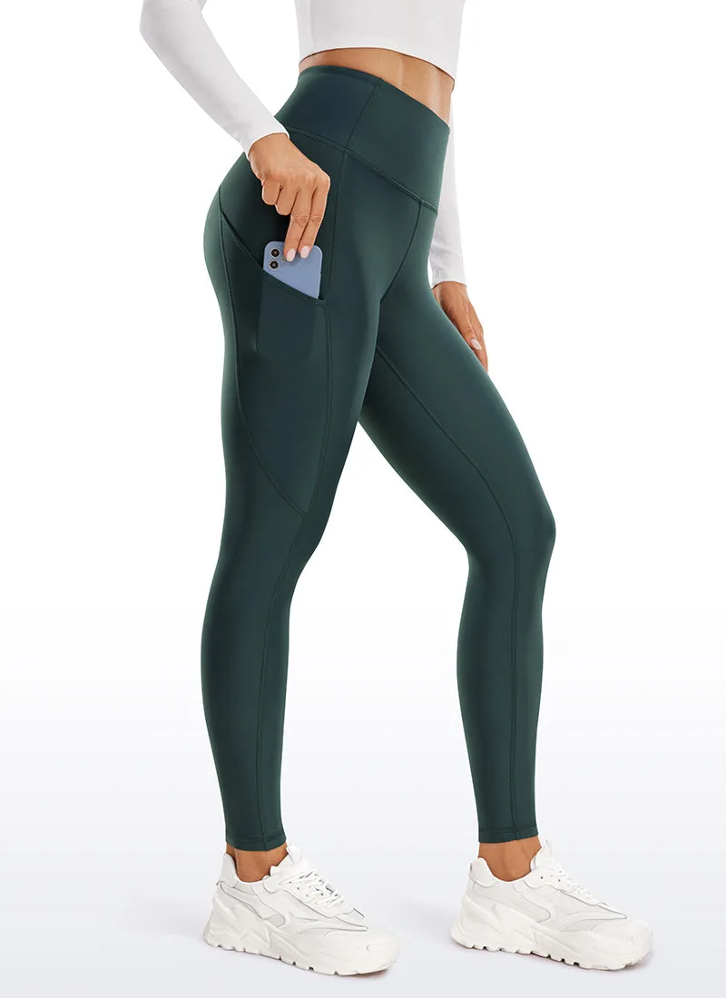 Dark green fleece lined legging photographed from the side as a pale blue phone slides into the side thigh pocket