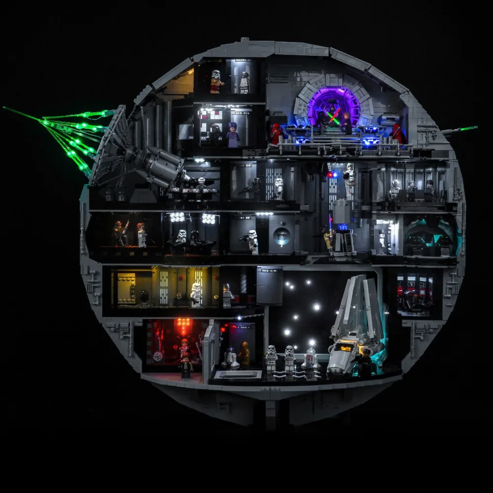 The LEGO Star Wars Death Star cross-section photographed in the dark, each interior room lit separately in white, blue, red and purple, with green beams running out from the superlaser dish