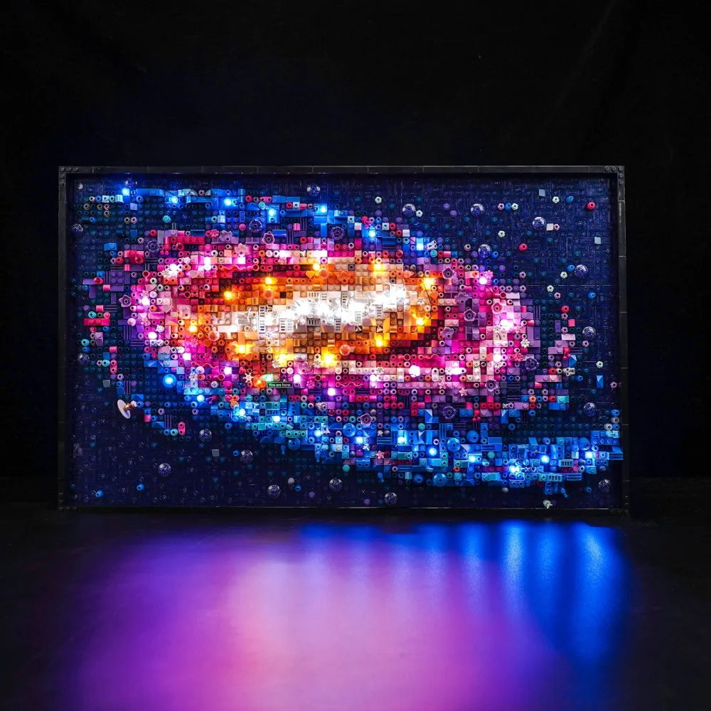 The LEGO Milky Way Galaxy brick mosaic backlit in the dark, a bright white and orange core fading into pink and blue spiral arms, with coloured light spilling onto the surface below