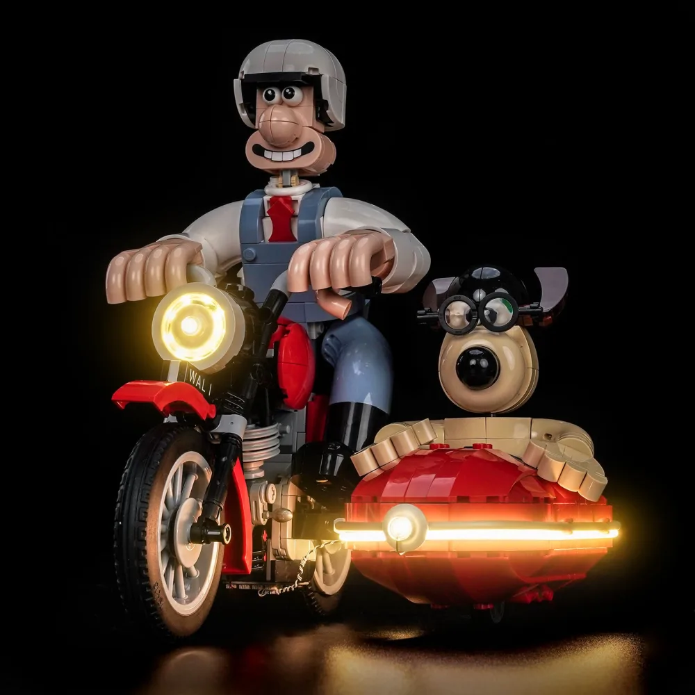 The LEGO Ideas Wallace and Gromit motorbike model in the dark, the round headlight glowing warm white and a lit strip wrapping around the red sidecar