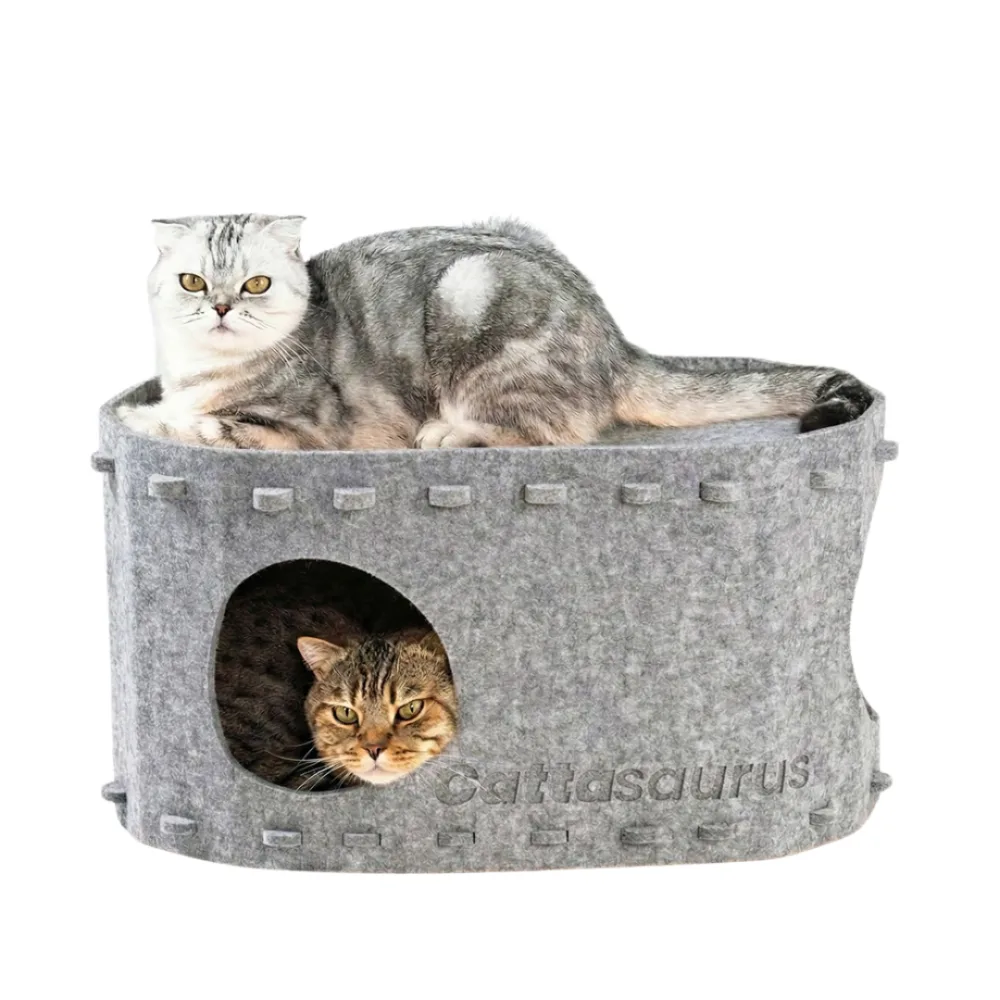 A two level grey felt cat bunk bed, one cat lying on the open top deck and a second cat looking out through a round hole in the lower level
