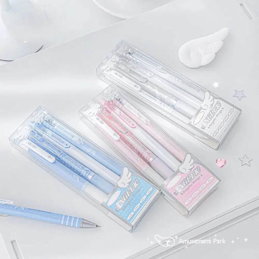 Best Journaling Supplies and Aesthetic Stationery: How to Build a Complete Kit in 2026 3 Three clear boxed sets of Angelic Shimmer gel pens in blue, pink and white, each box topped with a small white angel wing motif, arranged on a white surface