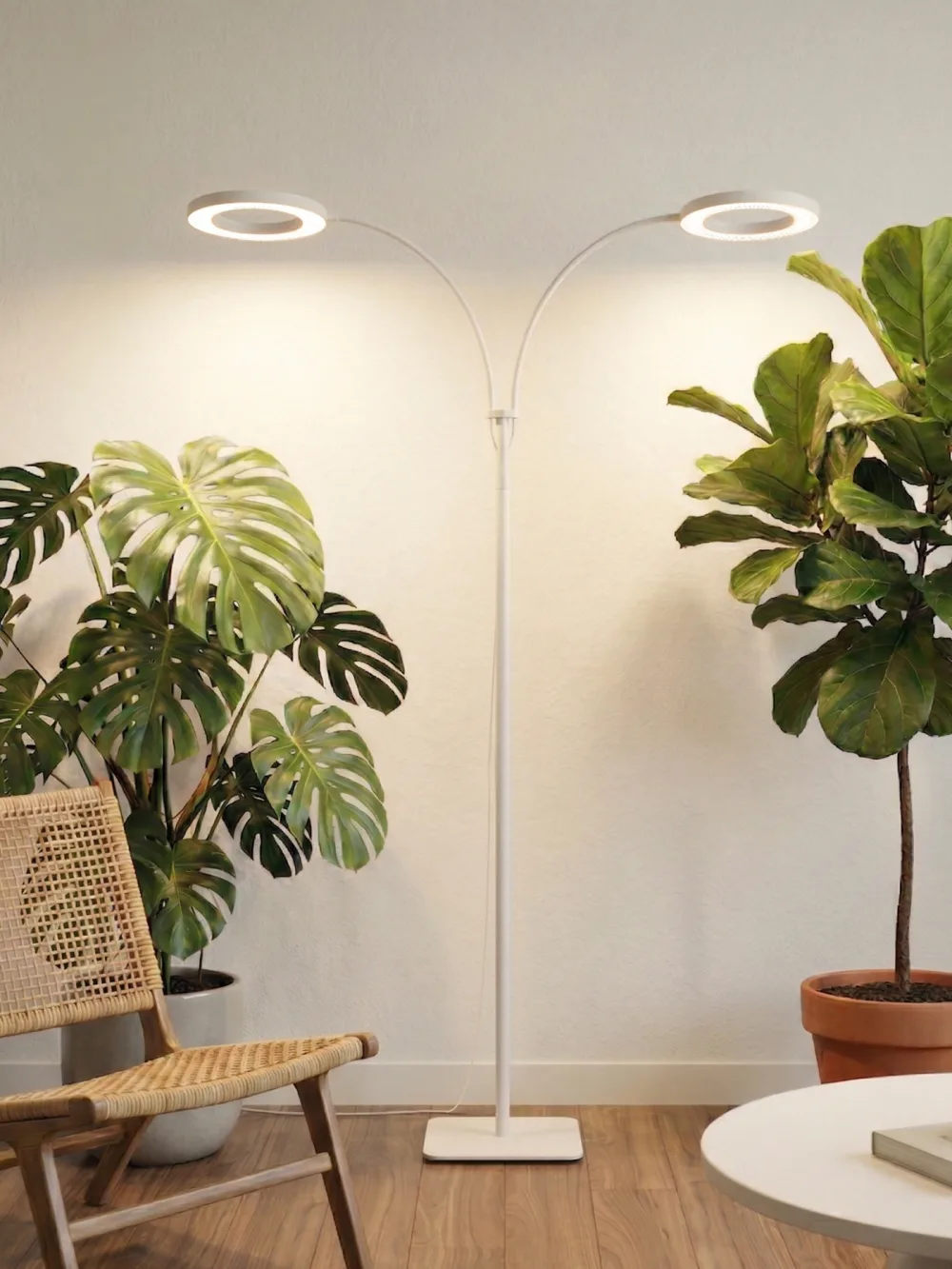 Glowrium G2 dual-head floor grow light standing between a monstera and a fiddle leaf fig in a living room, both ring heads lit and angled outward