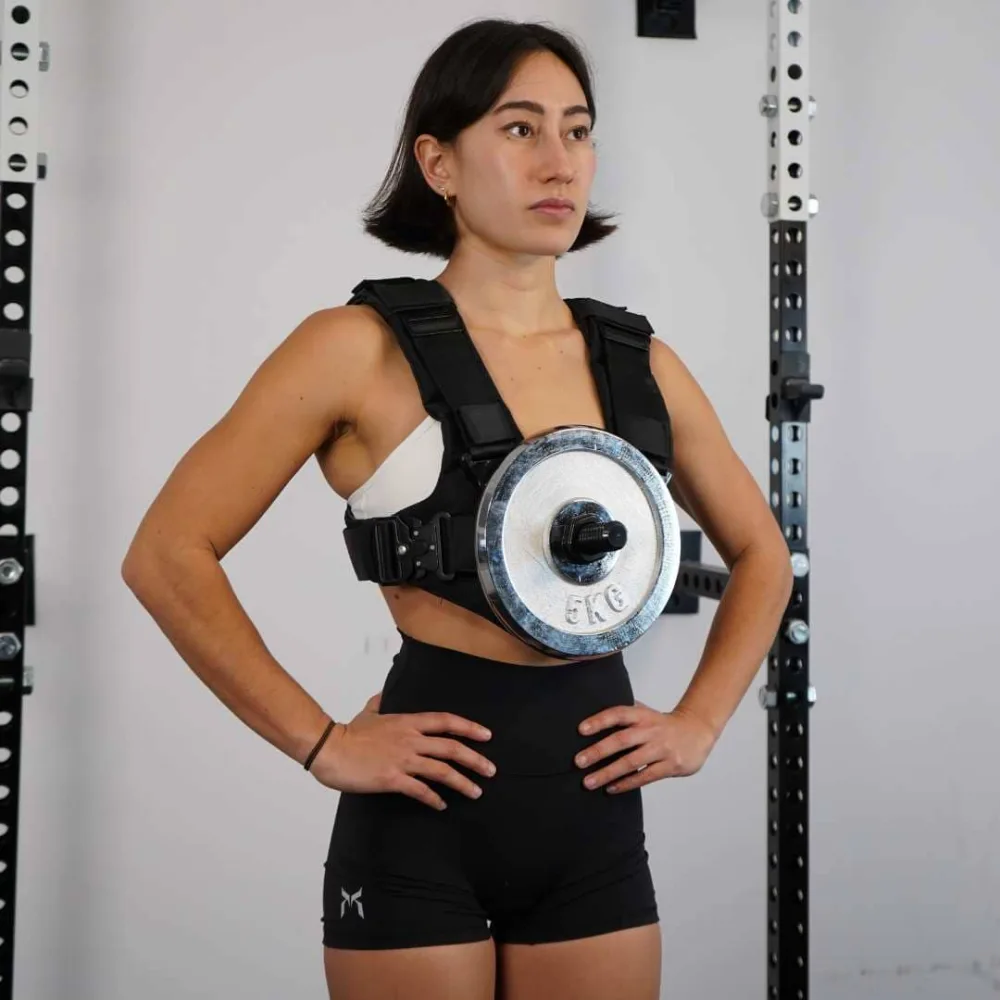 A woman wearing the EZ-VEST with a five kilogram standard one inch plate mounted on the front post using the adapter sleeve