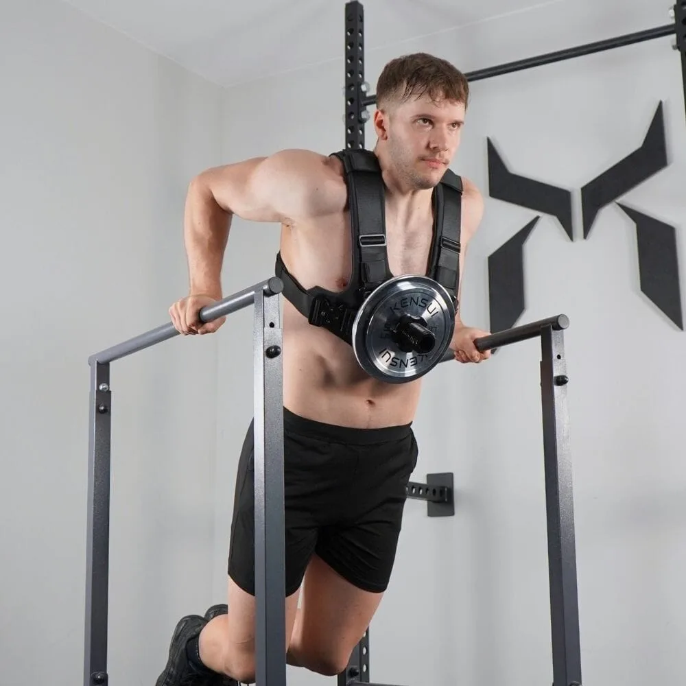 A man performing dips on a dip station while wearing the EZ-VEST with a single chrome Olympic plate loaded on the front post