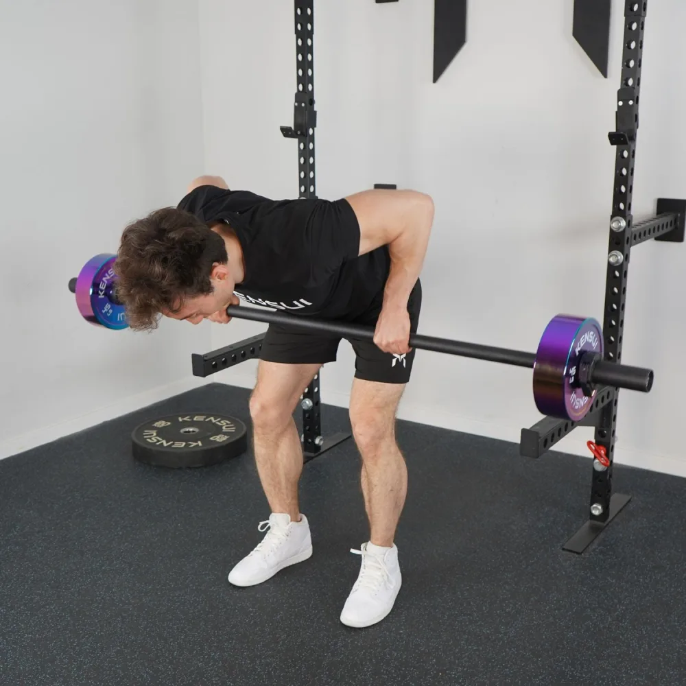 Best Specialty Barbells for Home Gyms: Trap, Swiss, Cambered and Buffalo Bars Compared 8 A man performing a bent-over row with the black powder coated Toyama Training Bar loaded with iridescent plates