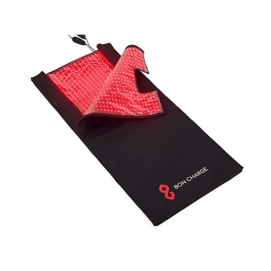 BON CHARGE Red Light Therapy Blanket folded partly open, the inner surface densely lined with lit red emitters and a wired handheld controller